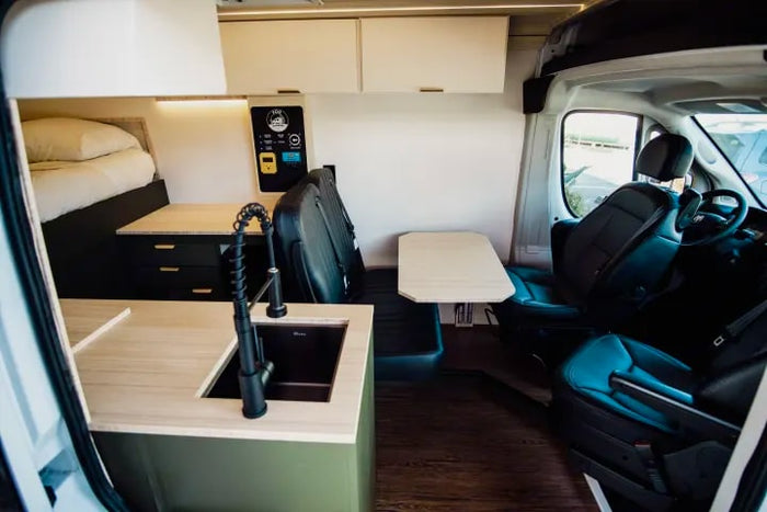 Modern RV rental interior with kitchen, bed, and dining area. Perfect for your next van life adventure!