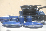 RV rental ready: Portable camp stove with a pan, blue enamel dishes, and utensils for outdoor meals.