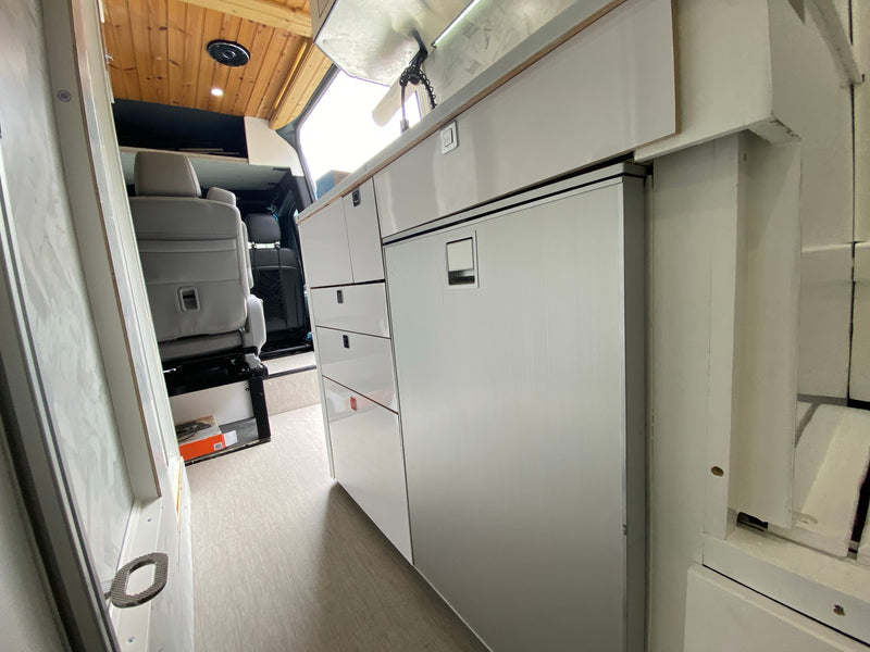  aiding parking by showing the vehicle and its surroundings.|RV rental interior: Sleek white camper van kitchen with fridge — photo 4