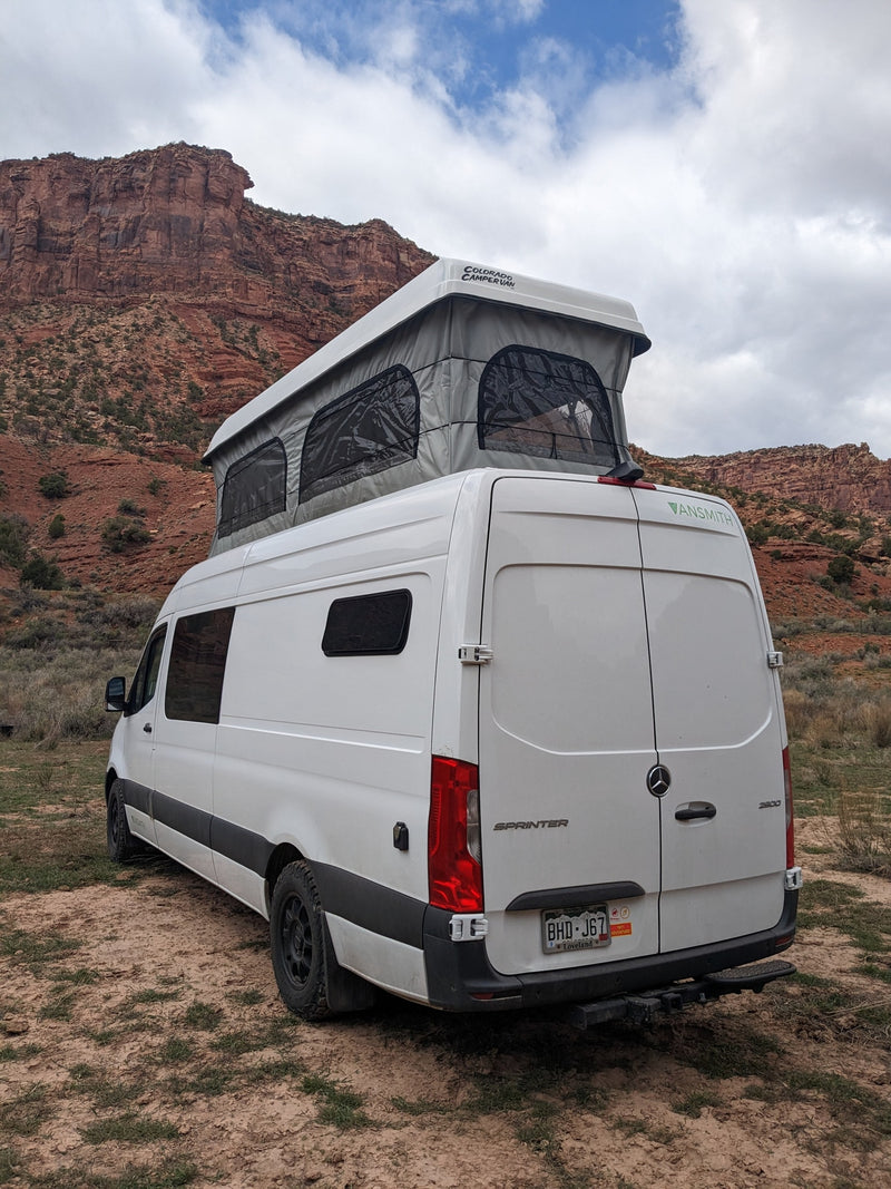 White Sprinter pop-top camper van for an RV rental, parked in a desert with red rock mountains. — photo 5