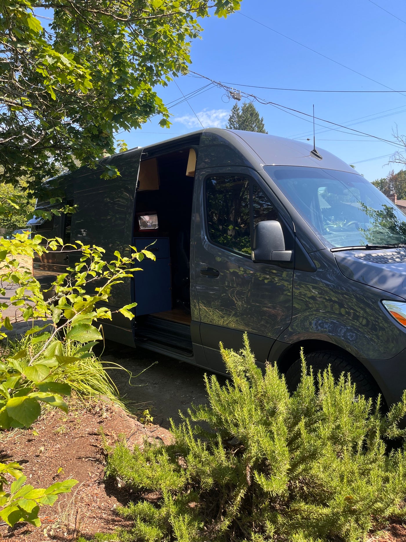 Dark grey camper van RV rental parked outdoors with side door open, showing interior. — photo 6