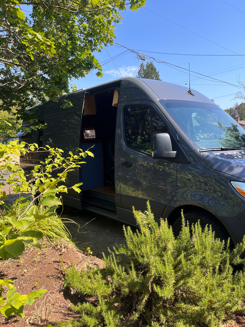 Dark grey camper van RV rental parked outdoors with side door open, showing interior. — photo 6
