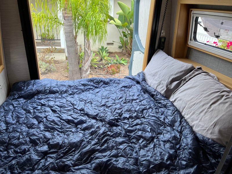 Cozy RV rental bed with a view of lush greenery outside. Ideal for a comfortable night's sleep during your adventure. — photo 12