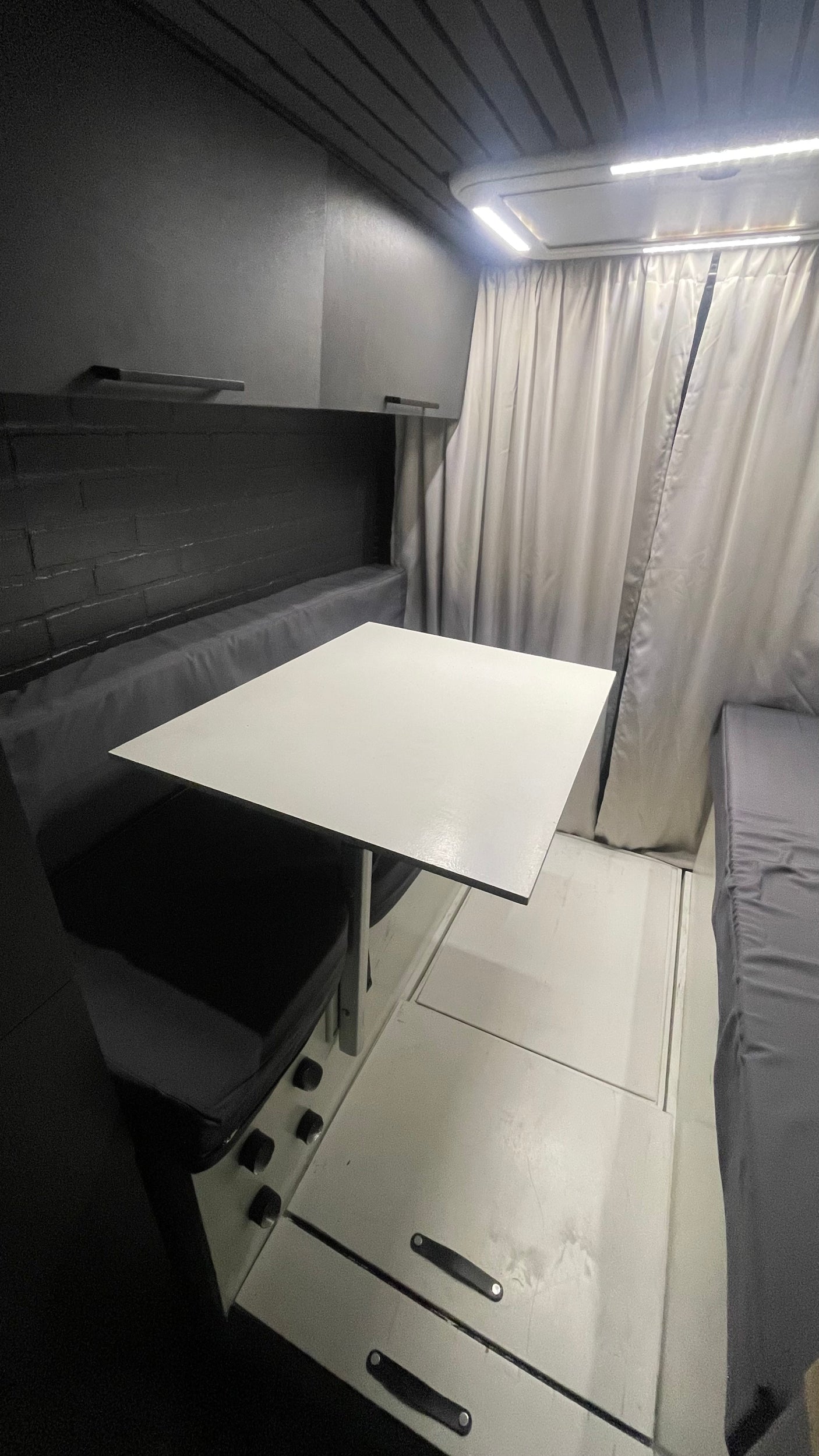 Spacious RV rental interior with a versatile dinette table, bench seating, and rear sleeping area.