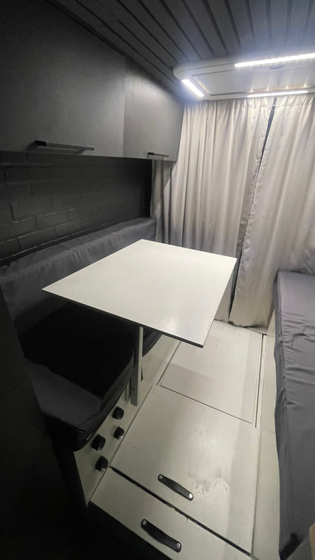 Spacious RV rental interior with a versatile dinette table, bench seating, and rear sleeping area.