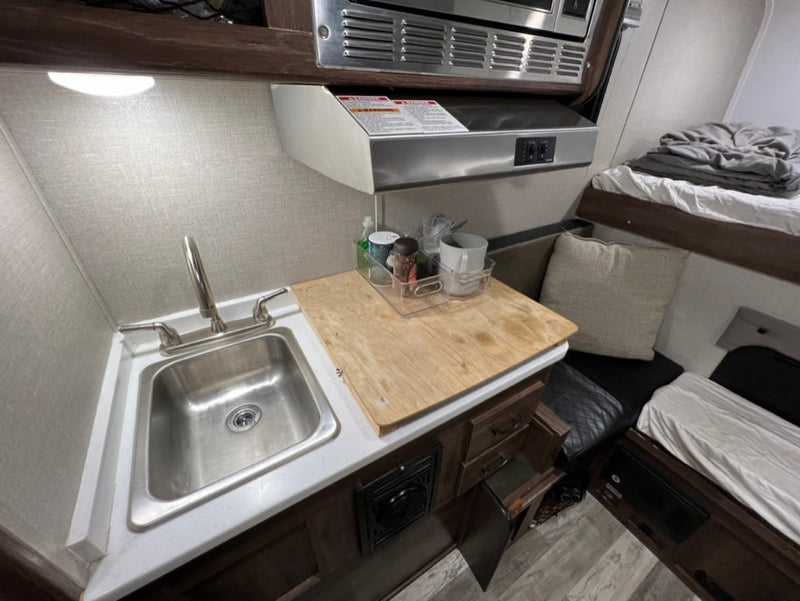  and sleeping area.|RV rental interior: A compact kitchen with microwave and sink — photo 7