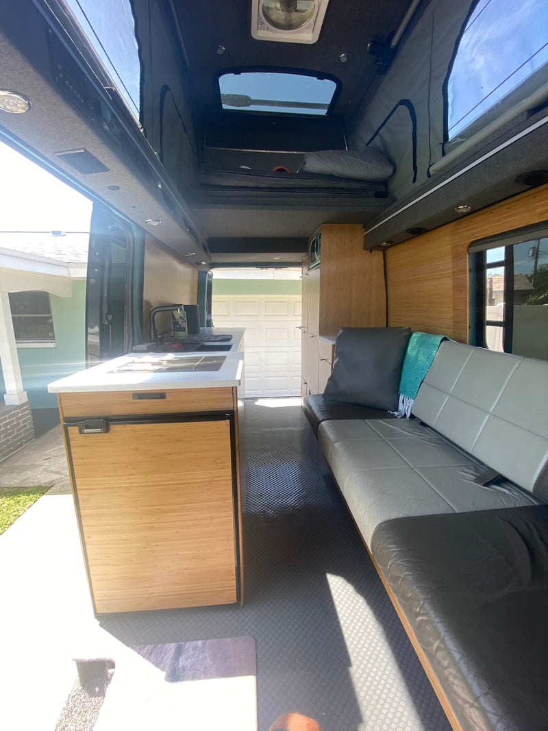 This RV rental offers a spacious interior with a full kitchenette, sofa, and pop-top bed, perfect for mobile living. — photo 9