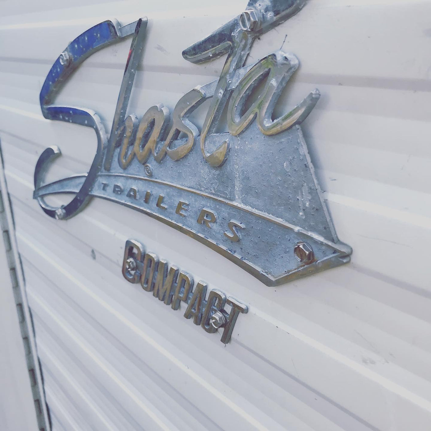 Vintage "Shasta Trailers COMPACT" emblem on an RV. A classic option for your next unique RV rental adventure!