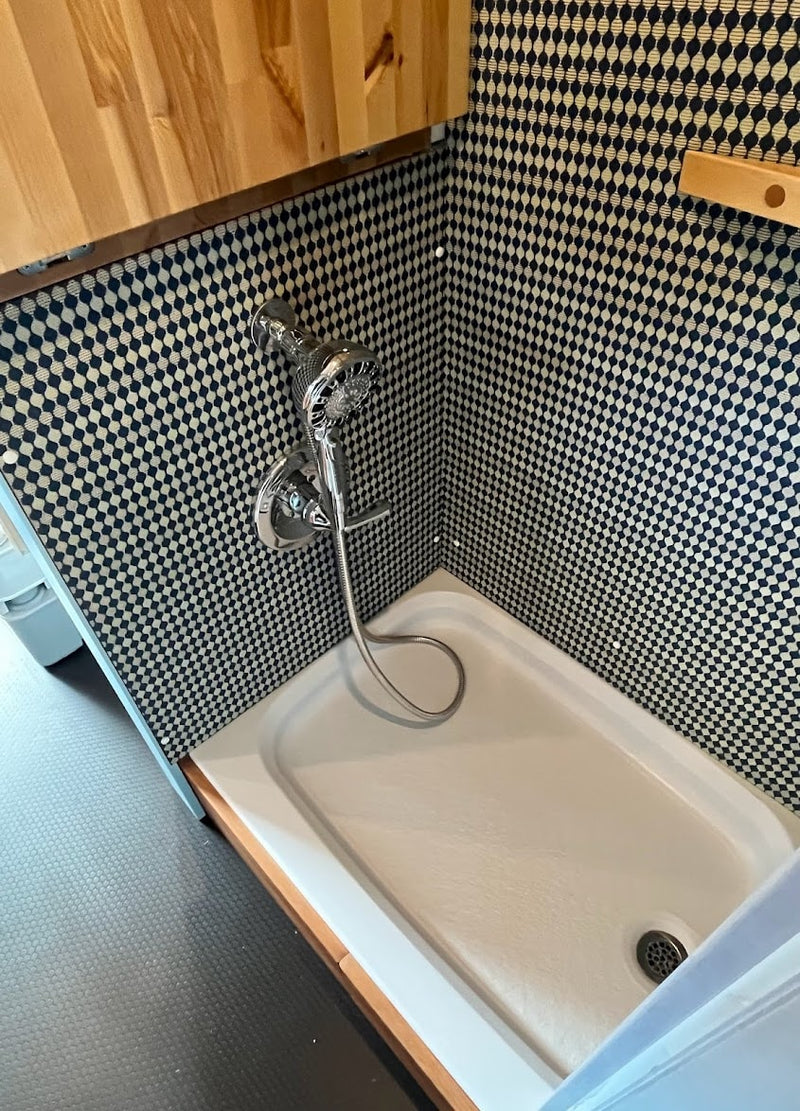 Modern RV rental shower with checkerboard walls, chrome shower head, and white pan. Compact and functional design. — photo 14