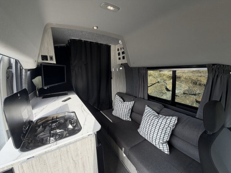  overlooking a scenic road and trees for mobile living.|RV rental: Camper van interior with kitchen — photo 5