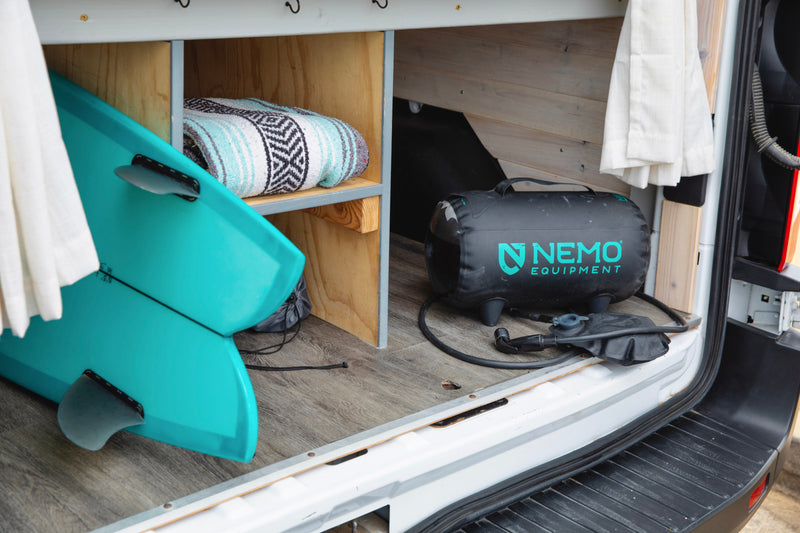 Inside this rv rental: surfboard, cozy blanket, and Nemo portable shower for surf and outdoor adventures. — photo 18