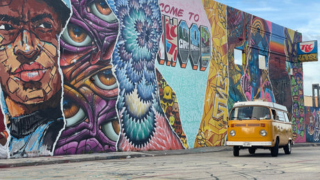 Dynamic street art mural and a vintage yellow VW Westfalia, an ideal RV rental for exploring vibrant urban landscapes.