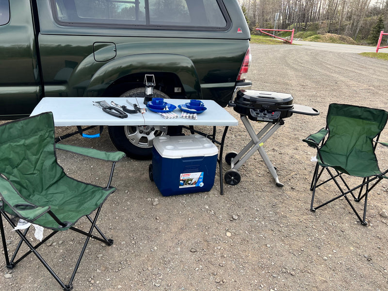 Outdoor camping setup with a grill, cooler, table, and chairs by a truck. Perfect for an RV rental adventure. — photo 11