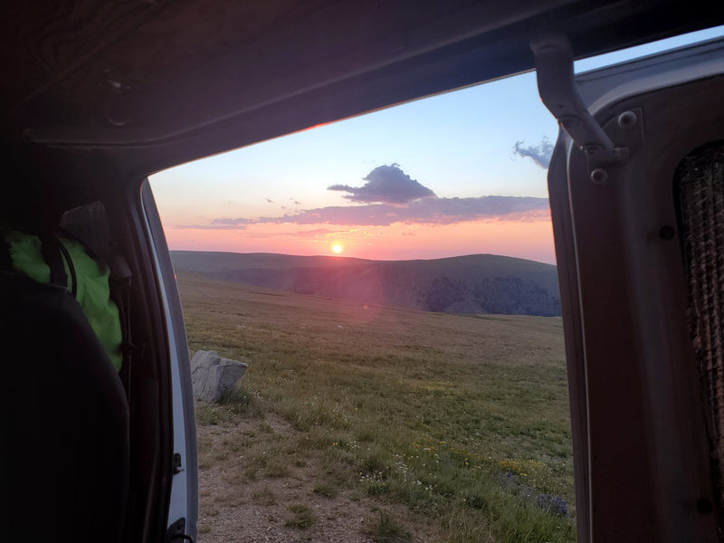  and portable fridge for adventure travel.|This RV rental offers a compact camper van interior with a bed — photo 12