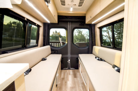 Spacious rv rental interior: A clean camper van cabin with comfortable benches, bright lighting, and wood accents.