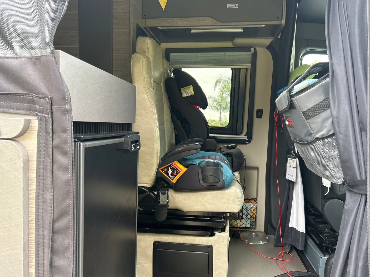 Inside this RV rental: A child booster seat, compact refrigerator, and storage in a camper van.