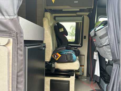 Inside this RV rental: A child booster seat, compact refrigerator, and storage in a camper van.