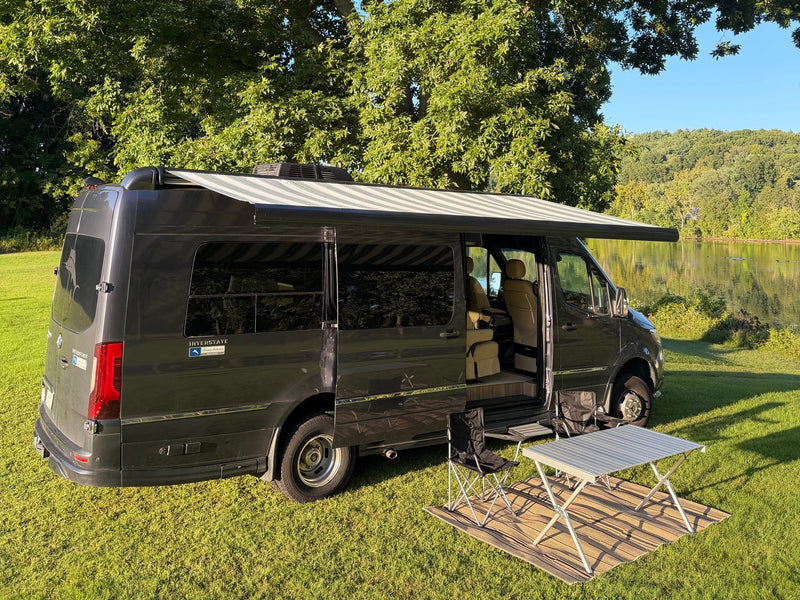  under a large tree in golden light.|An RV rental Mercedes Sprinter camper van with its awning extended and camp setup — photo 15