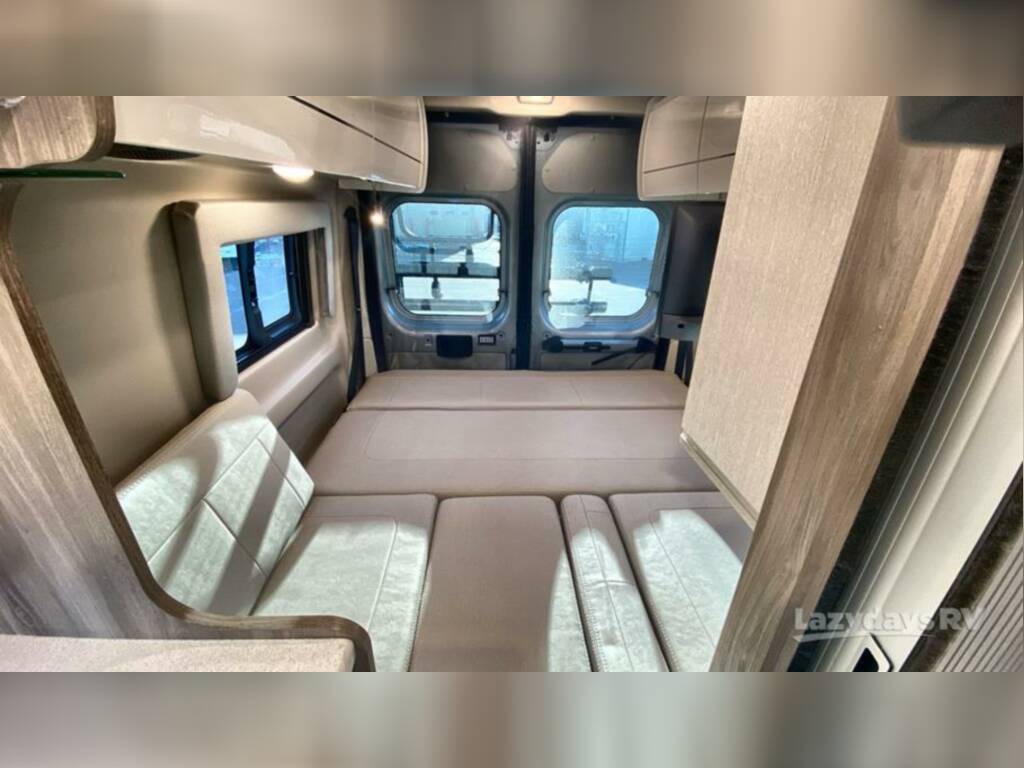  and glowing screen tent on green grass.|Inside a comfy RV rental: bed with patterned comforter — photo 9