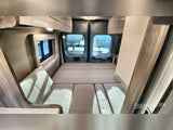 Get ready for adventure! This RV rental offers a comfortable, functional sleeping area with windows and storage in a camper van.