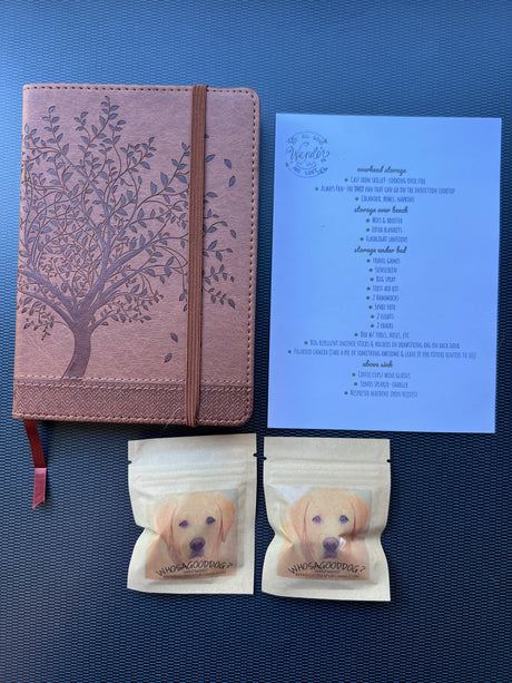 An RV rental welcome kit featuring a notebook, an amenities list for storage, and two bags of dog treats for guests.
