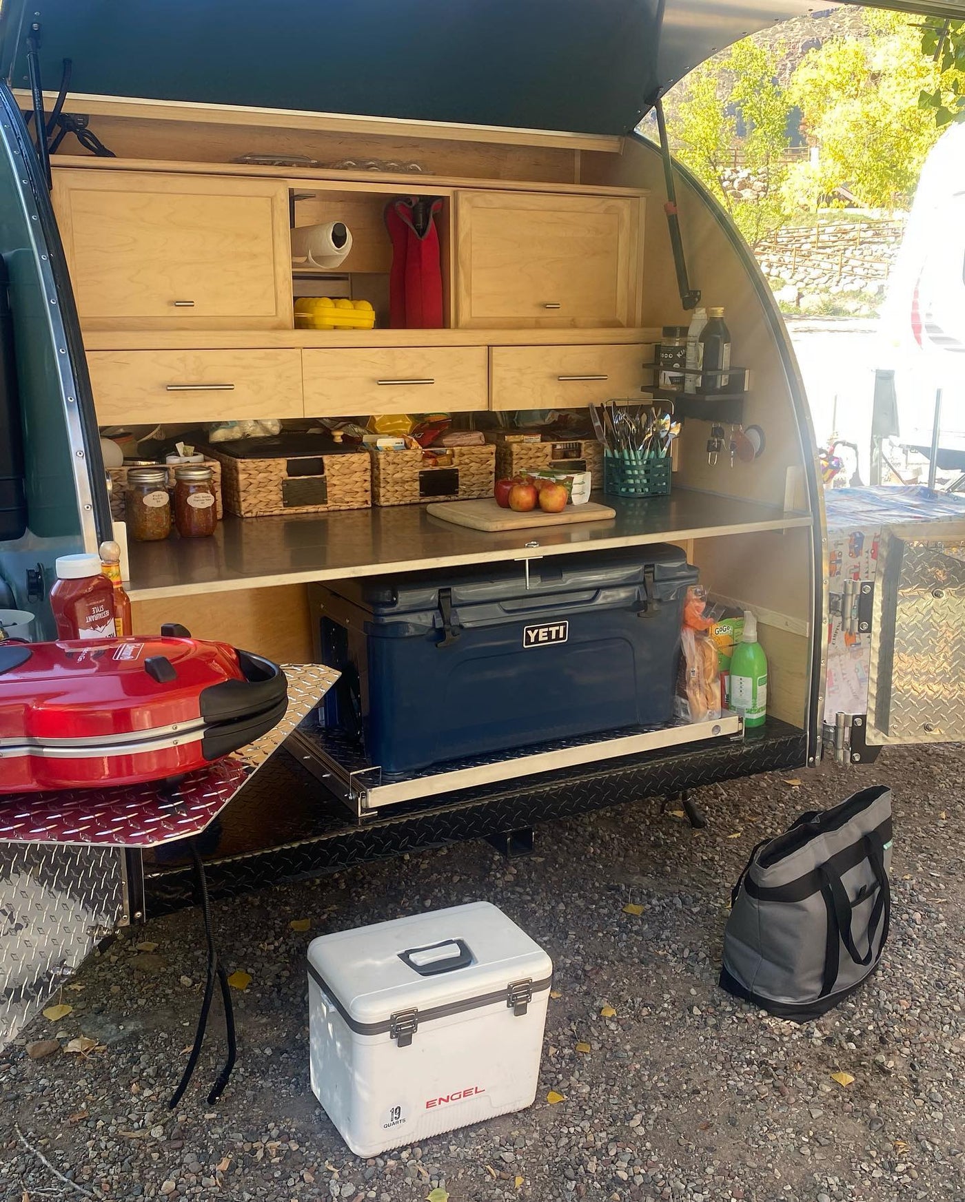 Well-equipped RV rental teardrop trailer's outdoor galley kitchen, featuring a Yeti cooler, grill, & organized storage. — photo 3