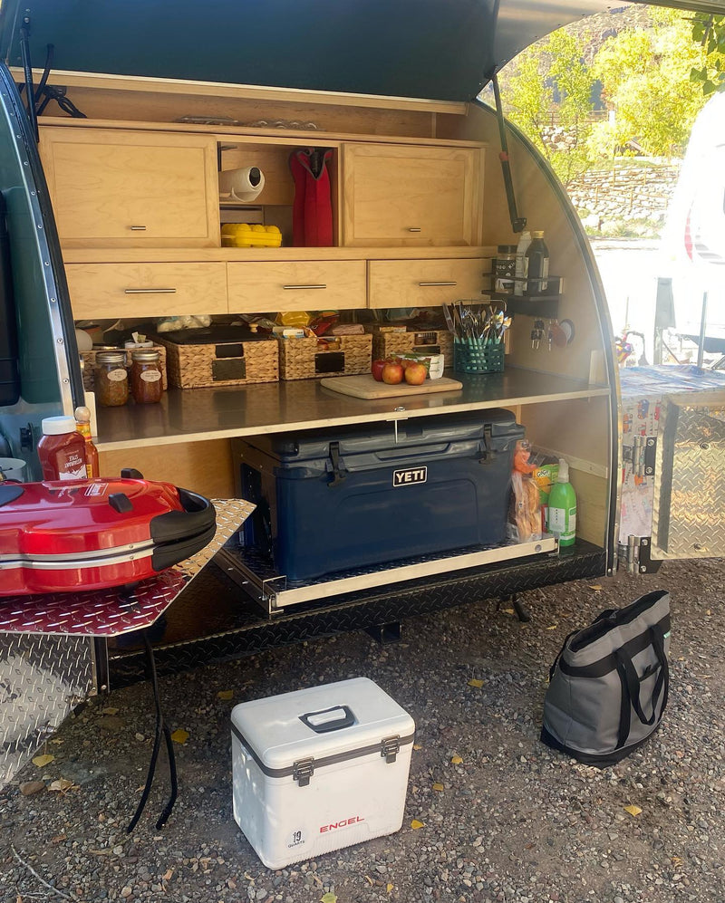 Well-equipped RV rental teardrop trailer's outdoor galley kitchen, featuring a Yeti cooler, grill, & organized storage. — photo 3