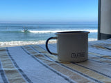 Morning coffee by the beach. This RV rental offers stunning ocean views, with a white 'TEXINO' mug on a striped blanket.