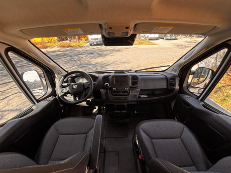 RV rental driver's view: Spacious cockpit with dashboard, steering wheel, seats, and street scene outside.