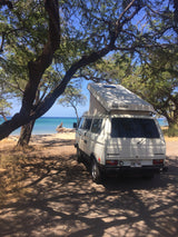 White VW Westfalia camper van RV rental parked at a scenic Hawaii beach with clear blue ocean. Perfect for island travel!