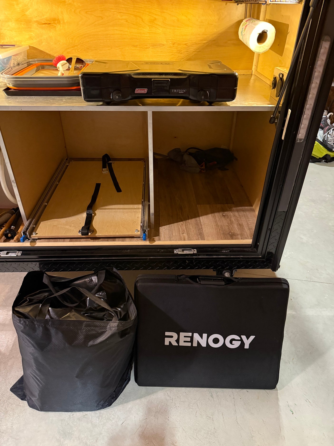 Compact rv rental kitchen & storage: portable stove, dish basin, Renogy power, and gear bag ready for adventure.