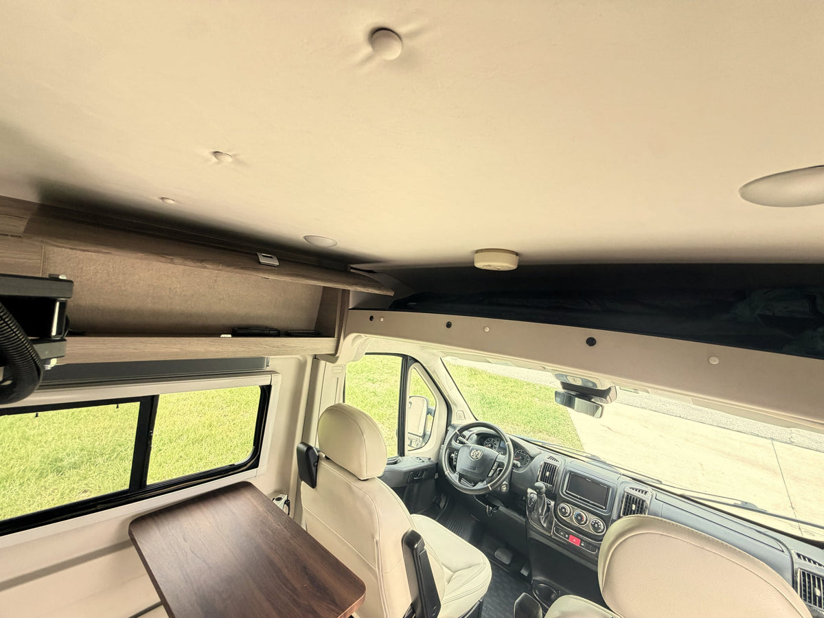  and cup holders.|Bright rv rental interior showing cream swivel seats — photo 13