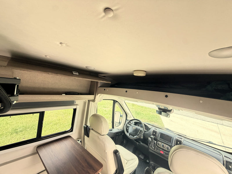  and cup holders.|Bright rv rental interior showing cream swivel seats — photo 13