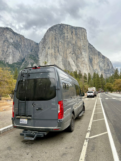 Grey Sprinter rv rental van parked roadside, facing towering El Capitan in Yosemite. Great mountain views.