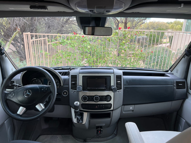  surrounded by snow & pines. Perfect winter motorhome adventure!|RV rental interior shot: view through windshield reveals front seats & a compact kitchen with a sink. Great for travel.|Explore this spacious RV rental! Side door open — photo 8