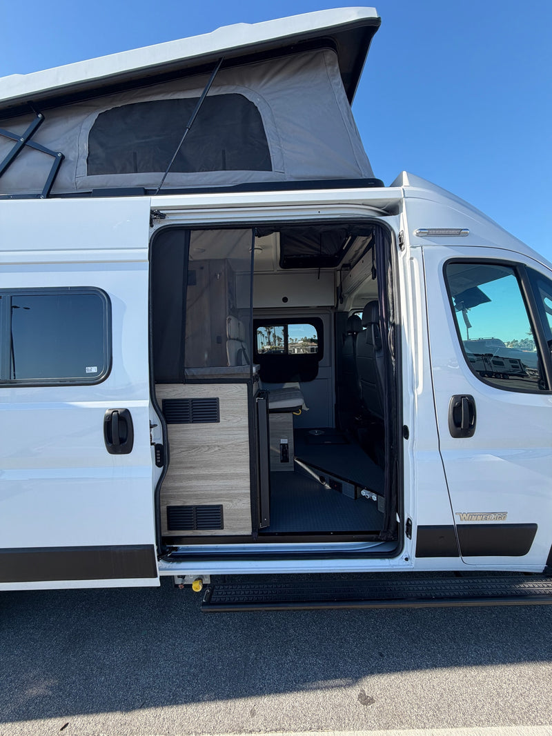  red flowers visible.|White Winnebago pop-top RV rental with open side door — photo 4
