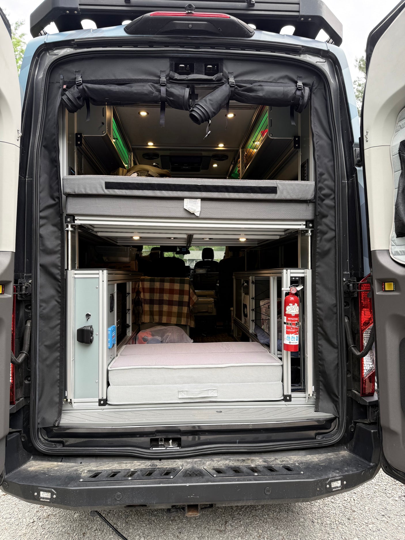 Rear view inside a custom camper van, highlighting its multi-level bed and storage setup for your next rv rental adventure.