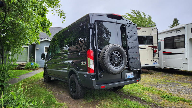 A black Mercedes Sprinter 4x4 van, equipped for adventure (possibly an RV rental), parked near other RVs. — photo 2