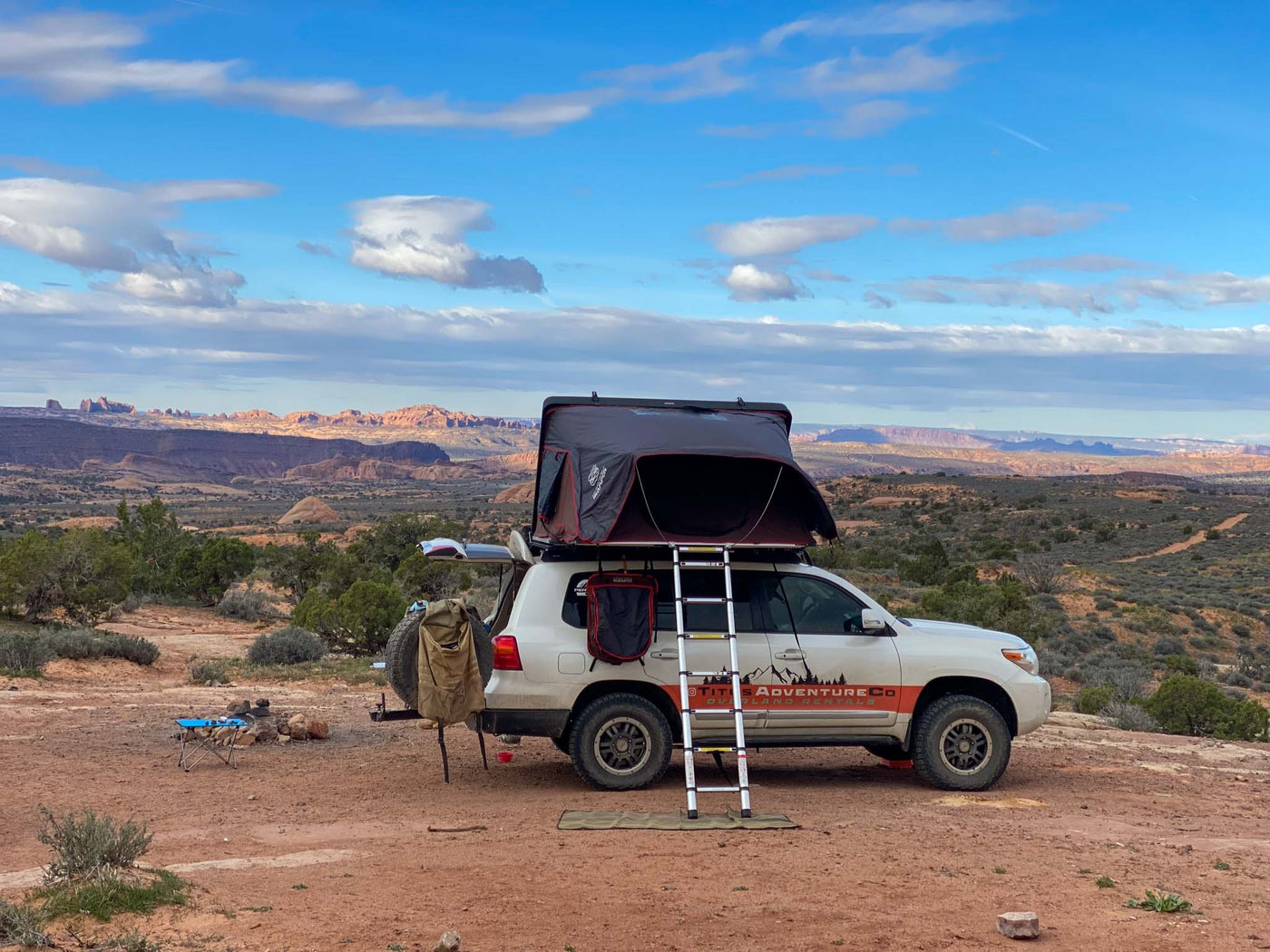  set against a stunning desert sunset.|White SUV **RV rental** with rooftop tent & ladder — photo 2