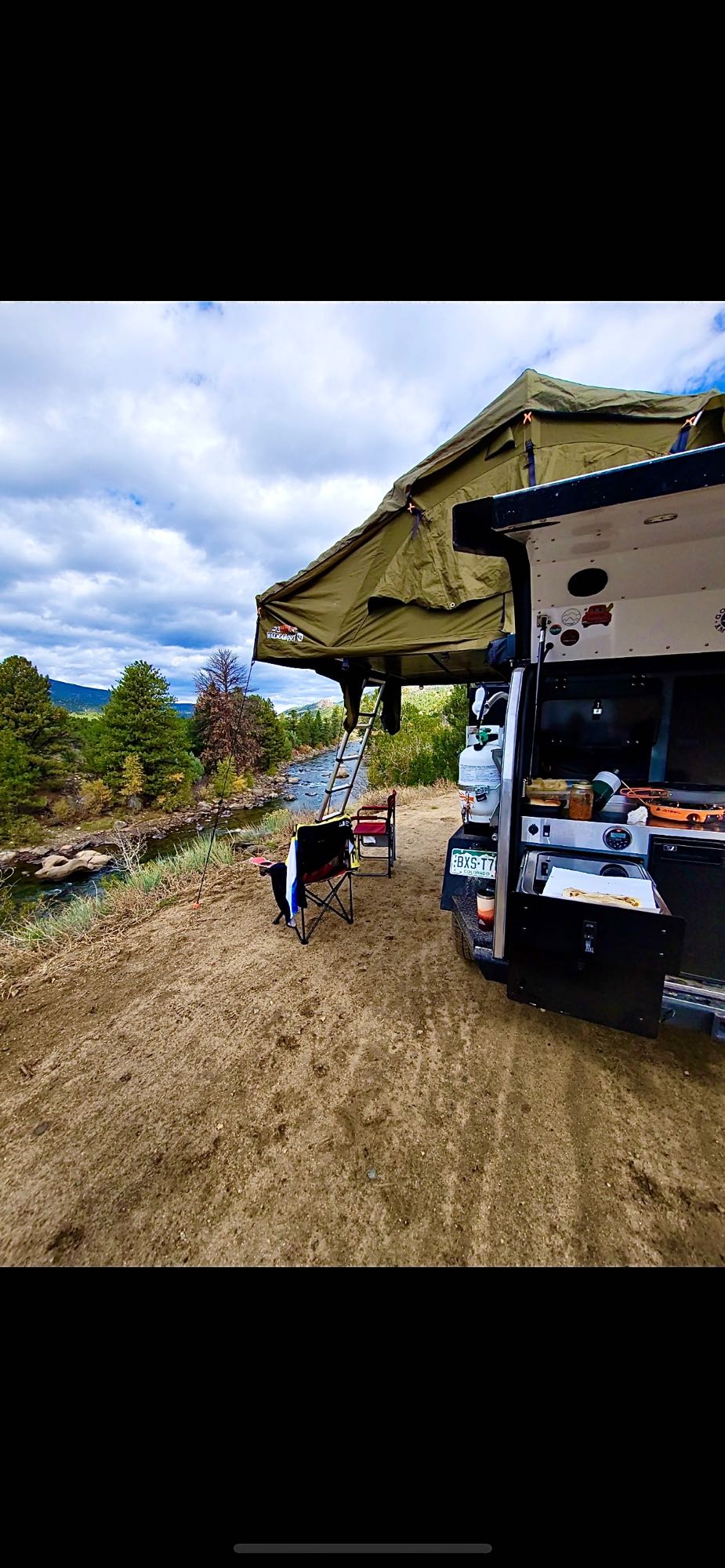 Overland RV rental setup with rooftop tent by a scenic river. Perfect for outdoor adventure & dispersed camping.