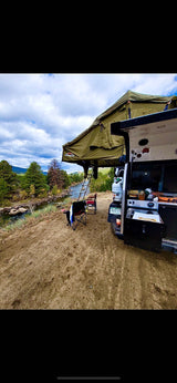 Overland RV rental setup with rooftop tent by a scenic river. Perfect for outdoor adventure & dispersed camping.