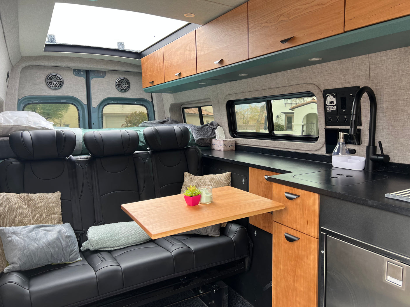 Spacious RV rental interior featuring black leather seating, a wooden table, and a well-equipped kitchen for trips.
