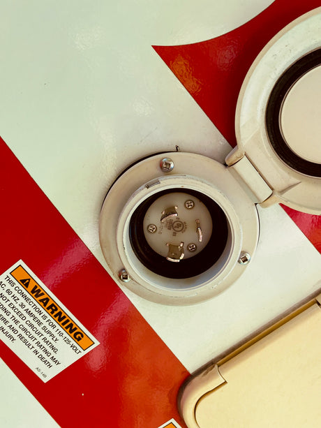 An RV rental shore power inlet with a warning for 110-125V, 30 amp supply. Essential for safe electrical hookup.