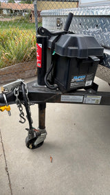 Front of an RV rental trailer, featuring a battery box, hitch, safety chains, and jack stand with wheel.
