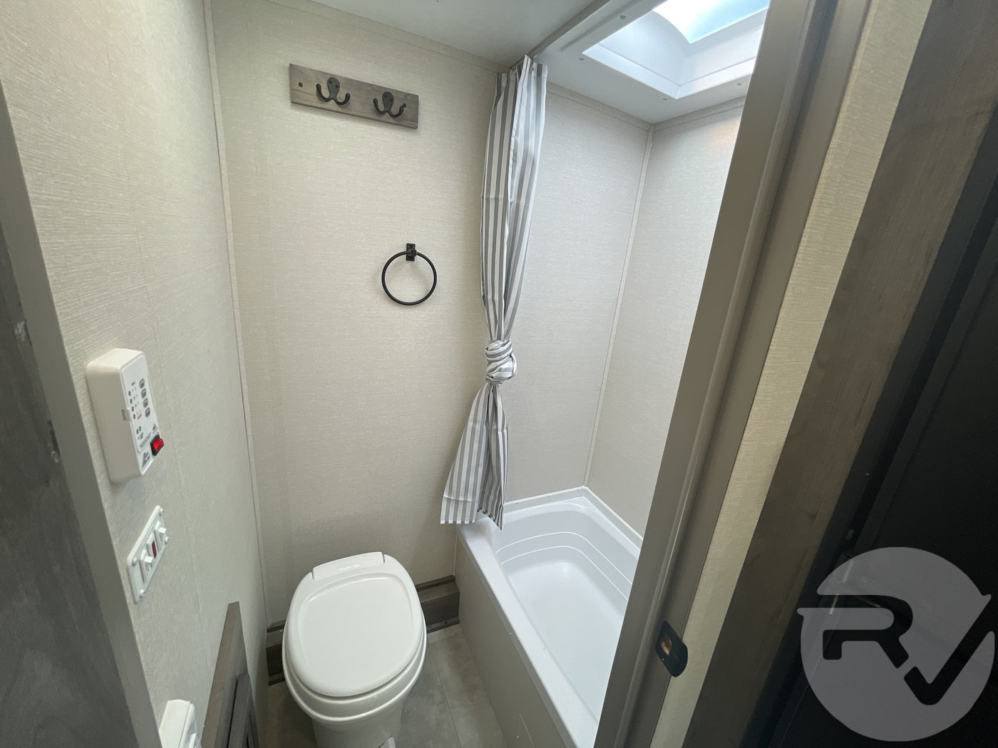 Inside an RV rental bathroom: features a compact toilet, shower/tub, and a skylight for a bright, functional space on the road. — photo 9