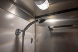 RV rental shower: A compact, brightly lit stall with a chrome shower head and sleek metallic/white walls for travel.