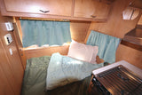 Experience this cozy RV rental's bedroom and kitchen. Features wooden interior, soft bedding, and natural light.