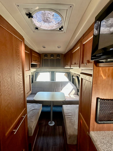 Inside an rv rental: inviting dining area with bench seats, overhead cabinets, and a ceiling fan for comfort.