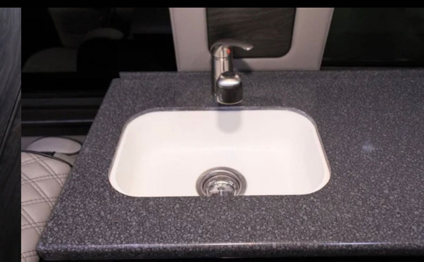 RV rental interior: A white sink with a sleek faucet set into a dark, speckled countertop. Functional and compact kitchen space. — photo 15
