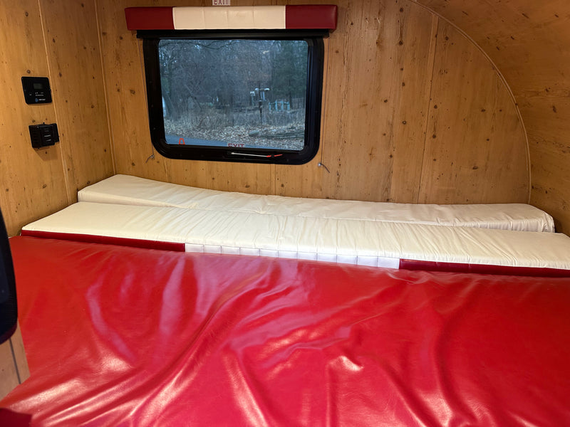 Inside an rv rental: wood interior, control panels, window, and red/white modular sleeping cushions. — photo 3